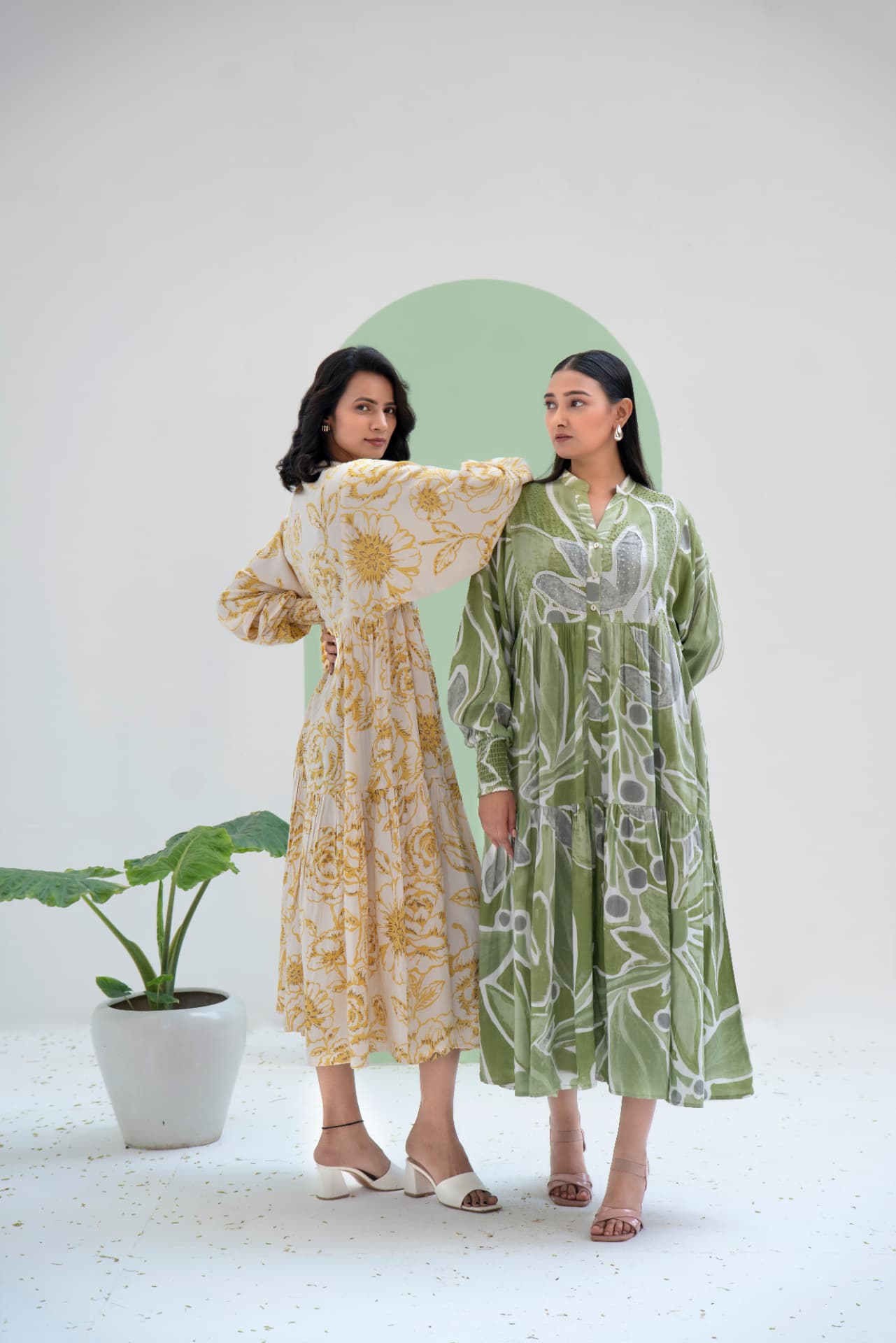 Two models in printed tiered maxi dresses in a white studio