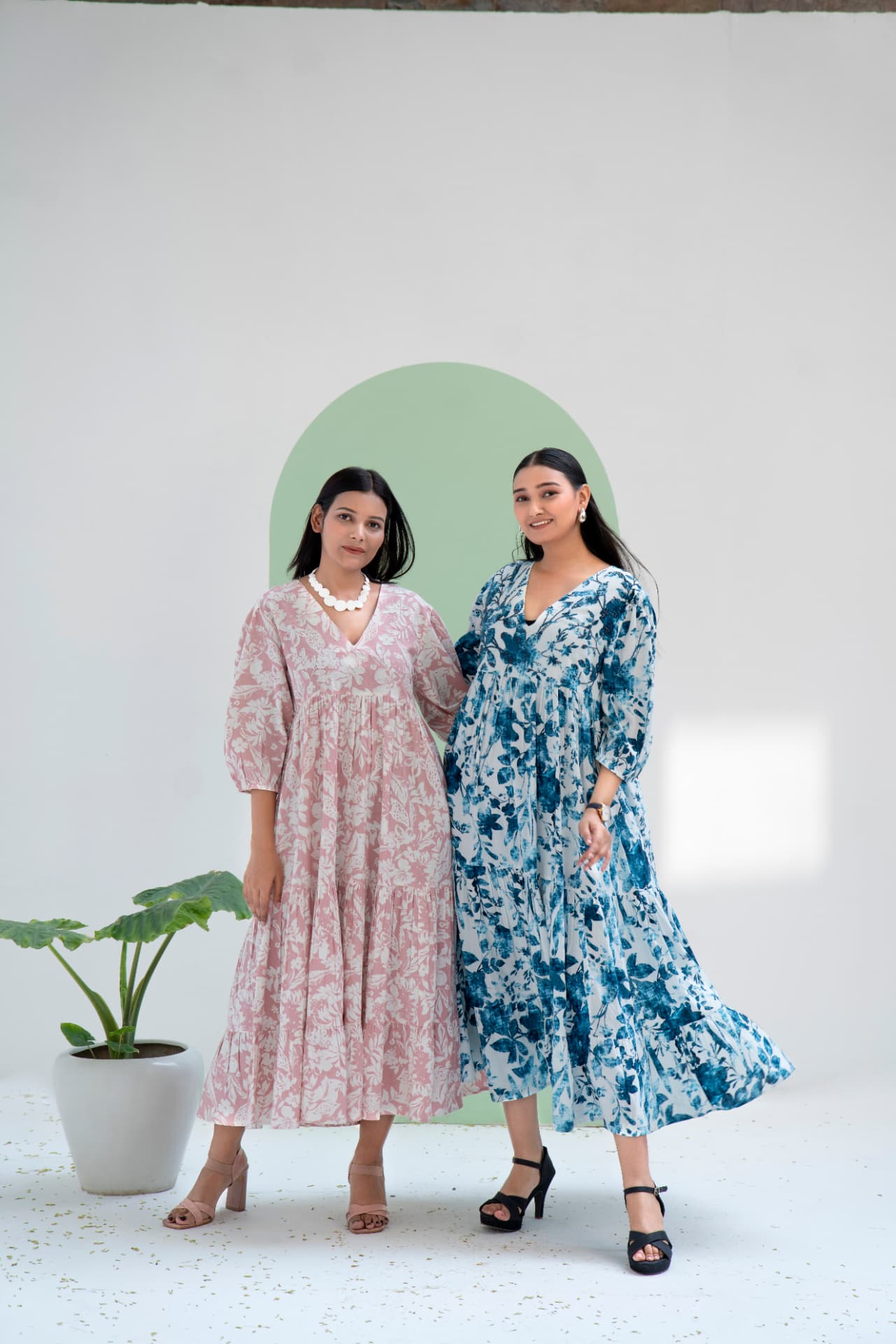 Two models in pink and indigo floral tiered dresses