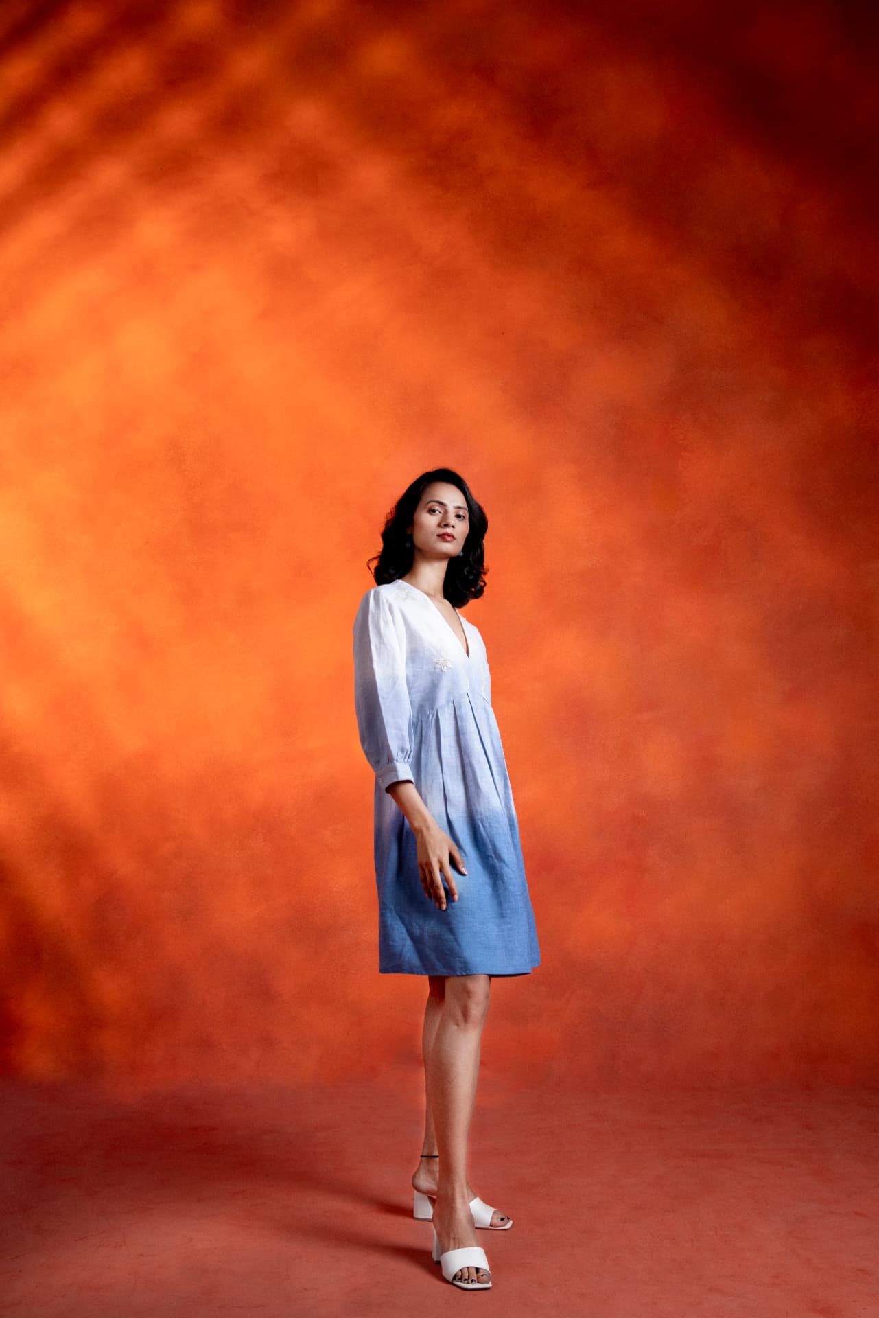 Model posing in an ombre linen dress under warm studio light